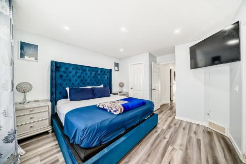 a bedroom with a blue bed and a flat screen tv at Cozy Vacation Home in Calgary