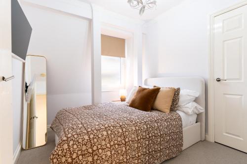 a white bedroom with a bed and a mirror at 90A Tower Road in Newquay