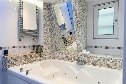 a white bath tub with a window and a mirror at 90A Tower Road in Newquay