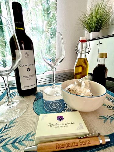 a table with a bottle of wine and two glasses at Residenza Serra in Villasimius