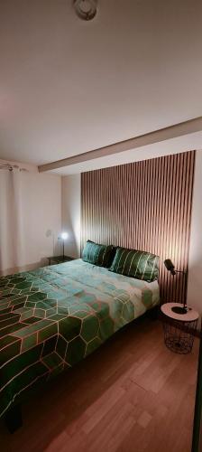 a bedroom with a bed with a green comforter at Le Liseo - Terrasse, véranda au cœur du centre ville in Niort