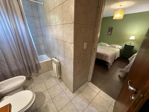 a bathroom with a toilet and a room with a bed at Paraiso Patagónico Bungalows and Aparts in El Calafate