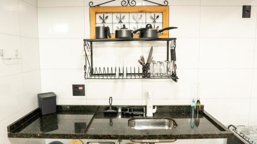a kitchen sink with pots and pans on a shelf at Jahu Center Casas Un 4 in Jaú
