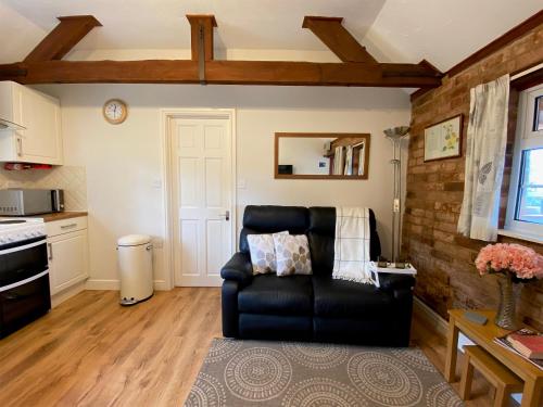 a living room with a black leather couch in a kitchen at Brown Snout in Ledbury