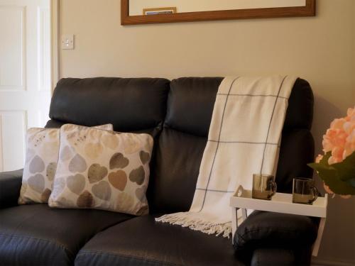 a black leather couch with a pillow and a blanket at Brown Snout in Ledbury