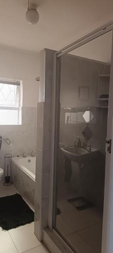 a bathroom with a shower and a tub and a sink at Accomodation in Cape Town in Goodwood