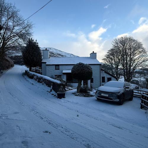 a car parked in front of a house in the snow at Maengwynedd, Llanrhaeadr Ym Mochnant in Oswestry