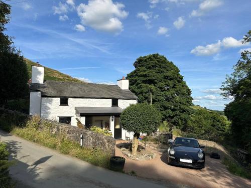 a car parked in front of a white house at Maengwynedd, Llanrhaeadr Ym Mochnant in Oswestry