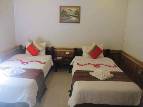 a hotel room with two beds with white and red pillows at Golden Lotus Place in Luang Prabang
