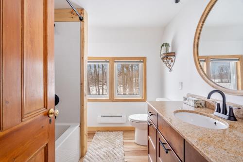 a bathroom with a sink and a toilet and a mirror at Strathmere Country Retreat in Ottawa