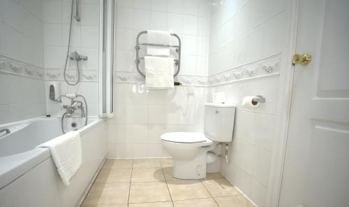 a white bathroom with a toilet and a bath tub at Consort Hotel & Urban Spa in Rotherham