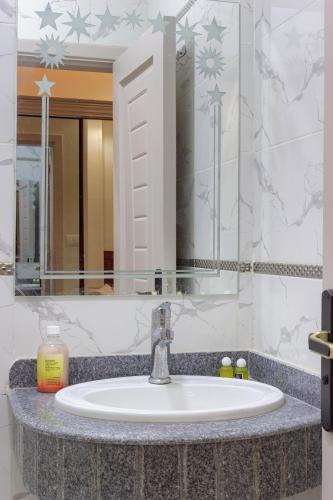 a bathroom sink with a large mirror above it at Hana Grand Hotel in Madinat Al Ashir min Ramadan