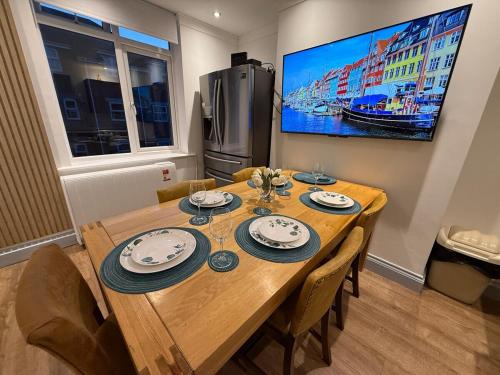 a dining room table with chairs and a tv on the wall at Spacious 4BR for Contractors, Groups, Families in Bournemouth