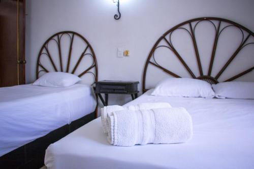 two beds in a room with two white towels at Hotel Posada del Angel in Mérida