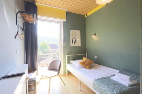 a bedroom with a bed and a desk and a window at Hotel Seeblick Obermaubach in Obermaubach