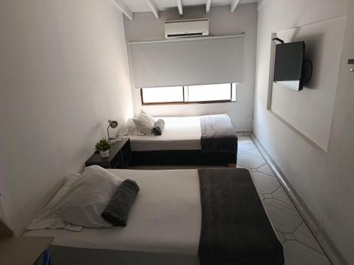 two beds in a small room with a tv at La Carpita Hotel in El Poblado