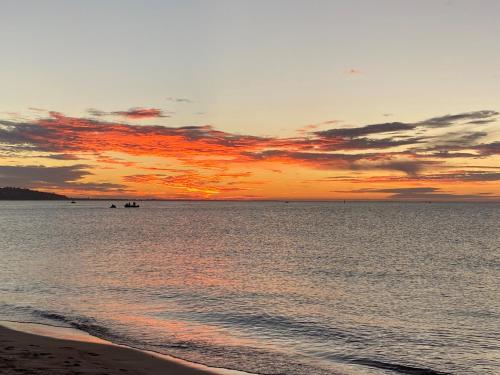 a sunset over the ocean with a sandy beach at Bay Motel Safety Beach in Safety Beach