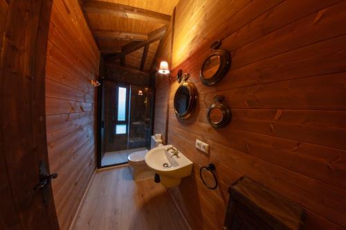 a bathroom with wooden walls and a sink and a window at Pensión Cabañas Bosque Máxico de Bonxe in Outeiro de Rei