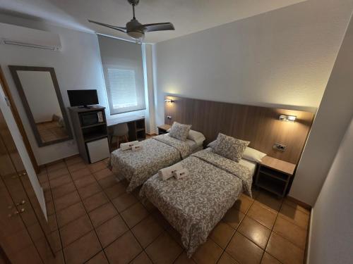 a hotel room with two beds and a television at Hostal De la Rosa by Parque Warner Madrid in Valdemoro