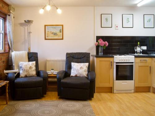 a living room with two chairs and a kitchen at Dabinett in Ledbury