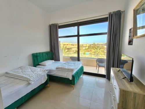 a room with two beds and a window with a view at View Pool Apartment, Two Rooms in El Gouna
