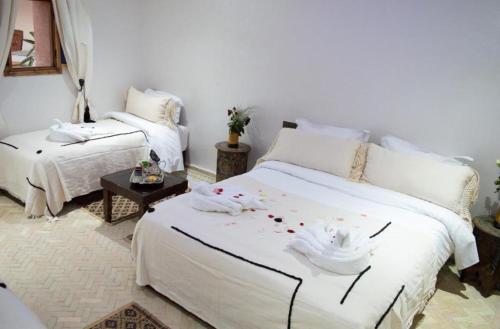 a bedroom with two beds with white sheets and a table at Villa Dar Saada in Marrakesh