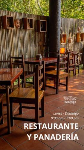 a restaurant with wooden tables and chairs and a fence at Reserva Ecologica Nanciyaga in Catemaco