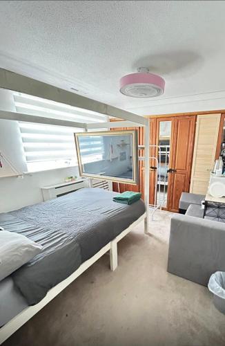 a bedroom with a bed and a tv and a couch at Room 3 minute drive from Luton Airport in Luton