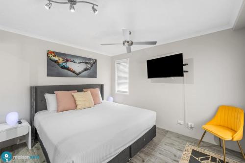 a bedroom with a bed and a tv on the wall at Burleigh Heads Koala Park Pool & Parking in Gold Coast