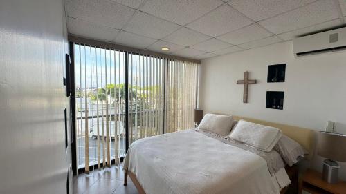 a bedroom with a bed and a cross on the wall at Departamento Frente al Salinas Yacht Club in Salinas