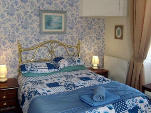 Un dormitorio con una cama azul y blanca con toallas. en Telford Manor House, en Beattock