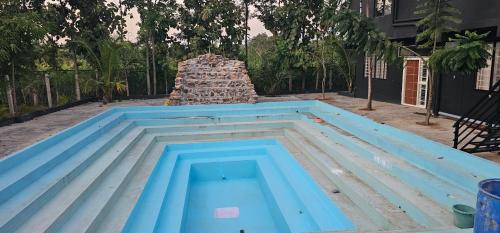 a swimming pool in front of a pile of bricks at Ambience Retreat in Malavalli