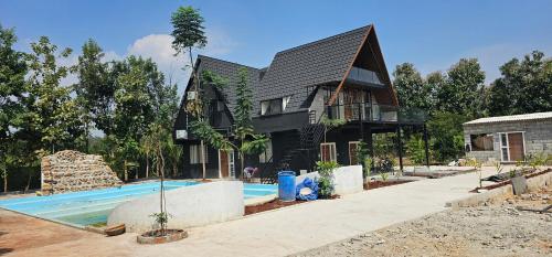 a house with a swimming pool in front of it at Ambience Retreat in Malavalli