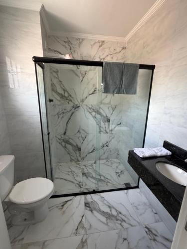 a bathroom with a shower and a toilet and a sink at Hotel Pousada Romanos in Aparecida