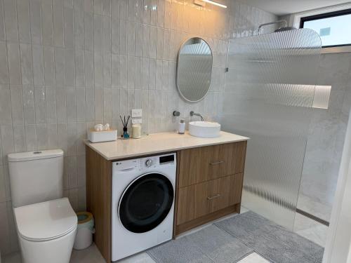 a bathroom with a washing machine and a sink at Banksia apartment - Escape to Serene Rural Bliss! in Inverell