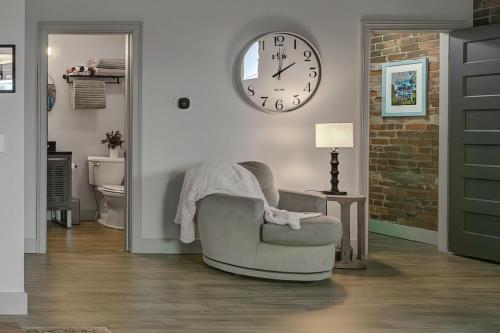 a living room with a chair and a clock on the wall at The 418. An 1866 Build with Modern Comforts in Fort Wayne