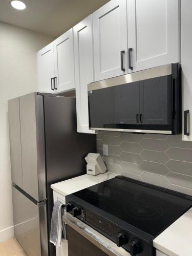 a kitchen with a black refrigerator and white cabinets at Home at Haven in Phoenix