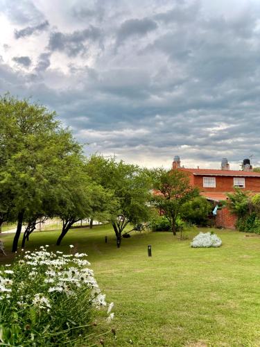 a field of grass with trees and a building at Casas de campo Traslasierra in Villa Cura Brochero
