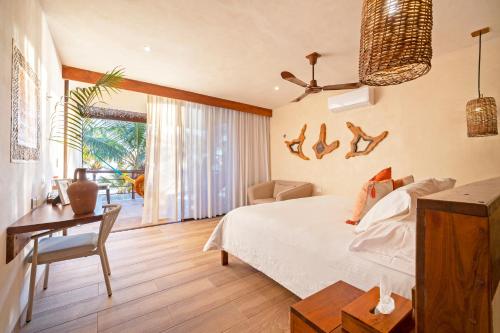 a bedroom with a bed and a table and a desk at Los Arrecifes in Tulum