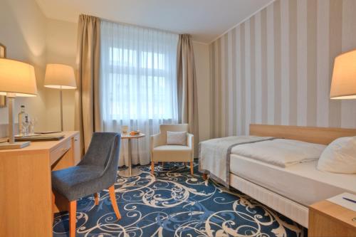 a hotel room with a bed and a desk and chair at Schlosshotel Karlsruhe in Karlsruhe