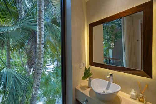 a bathroom with a mirror and a sink and a palm tree at Los Arrecifes in Tulum