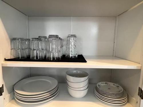 a cupboard with plates and glass jars and dishes at 25 Lux Room 6 - 1 Queen Bed, Shared Bathroom - Nonsmoking in Arlington