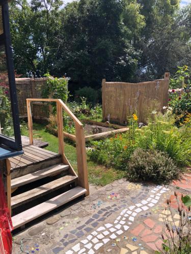 a wooden staircase in a garden with a fence at Dragon's Den - self contained unit in Takaka