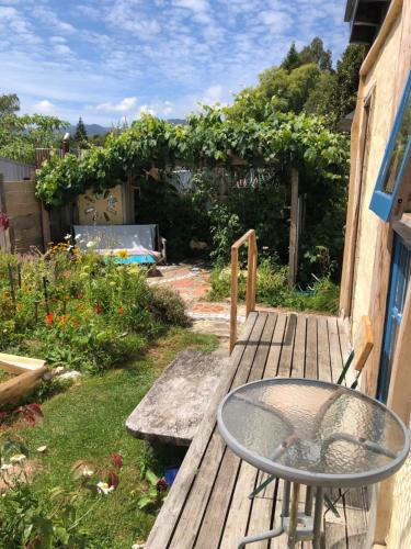 a wooden deck with a table and a garden at Dragon's Den - self contained unit in Takaka