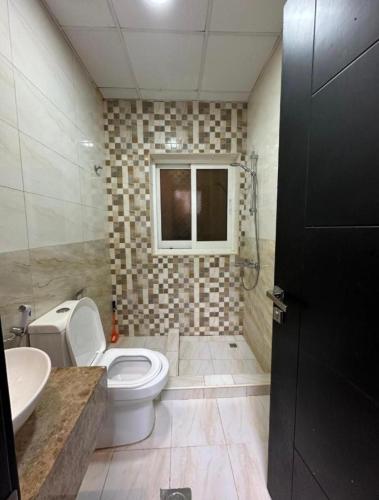 a bathroom with a toilet and a sink and a window at Entire Studio Apartment with King Bed in Ajman 