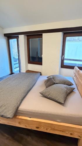 ein großes Bett in einem Zimmer mit Fenstern in der Unterkunft Schmuckes Rustico in Pianezzo