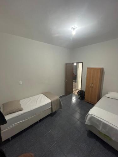 a bedroom with two beds and a cabinet in it at Casa BIG John 4 Bahia in Divinópolis