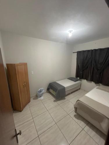 a bedroom with two beds and a cabinet in it at Casa BIG John 5 Bahia in Divinópolis