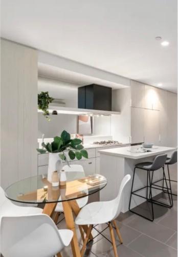 a kitchen with a glass table and white chairs at City Vibe on Dorcas Southbank in Melbourne