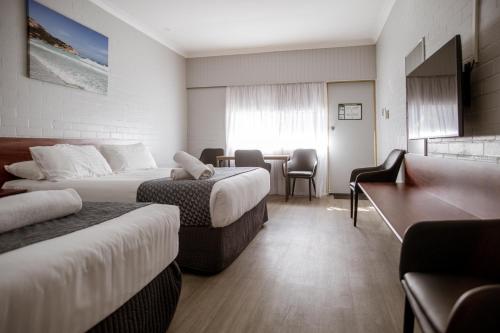 a hotel room with two beds and a desk at Bayview Motel in Esperance